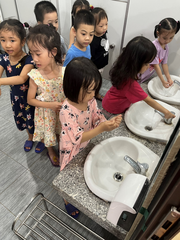 A group of children stand around a sink

Description automatically generated with low confidence